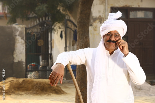 man sitting in Rural wearing kurta-pajama which is traditional Dress for men in North India in day time & Enjoying talking on mobile phone photo