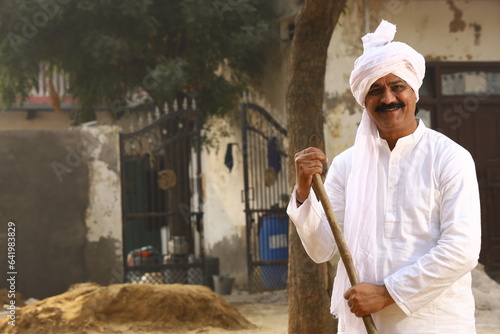 Mid-Aged man in Rural Environment wearing kurta-pajama which is traditional Dress for men in North India in day time holding walking cane. photo