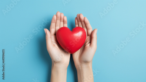 woman hand with red heart in studio on blue background.