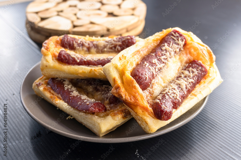 puff pastry with sausage on a black background. diet. food concept.mini pizza. puff pastry with sausage on a black background. diet. food concept.mini pizza.