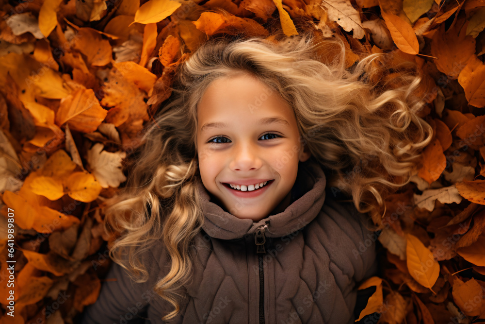 Cute blond girl laying in autumn leaves 