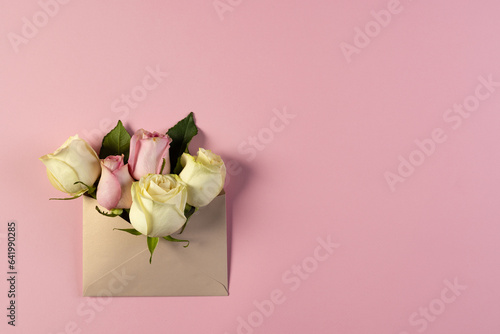 White and pink rose flowers in brown envelope and copy space on pink background