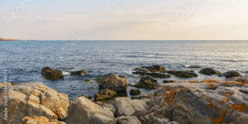 seashore with rocks at sunrise. bright morning sky above horizon. sunny weather