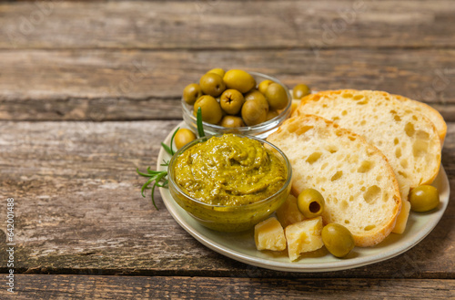 Ciabatta and olives. Fresh italian ciabatta bread with herbs, olive oil,parmesan and pesto sauce, olives on wooden background, top view, copy space.Flatley. Place for text. copy space.