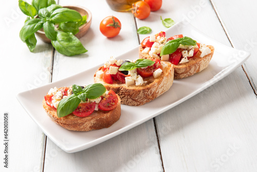 Fototapeta Naklejka Na Ścianę i Meble -  Deliziose bruschette mediterranee alla caprese, bruschette con pomodoro, mozzarella, basilico, olive nere, olio di oliva e origano, cibo italiano 