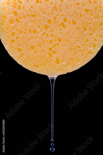 Extreme close up of yellow makeup sponge dripping water
