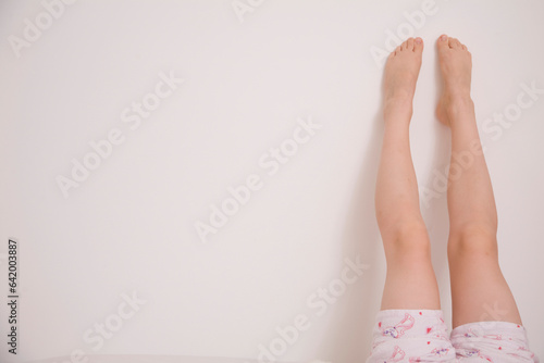 One pair of legs up a white wall
 photo