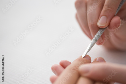 Close up of manicurist's hand pushing woman's cuticles with cuticle pusher
 photo