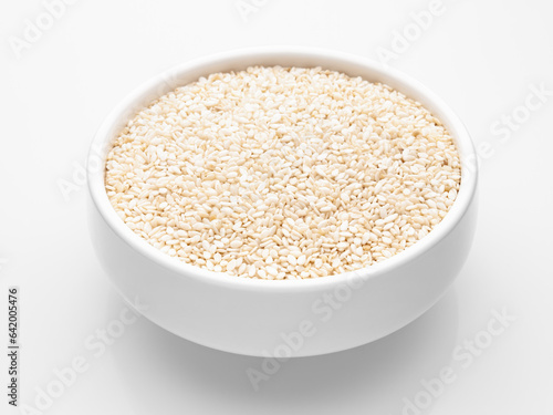Close-up white sesame seeds in a white round deep bowl on a white background. Healthy food. Selective focus.