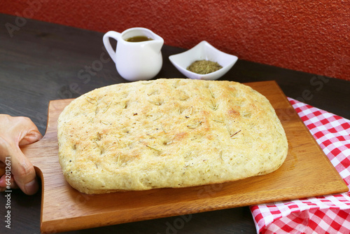 Hand Placing Delectable Freshly Baked Herbed Focaccia Bread on the Table photo
