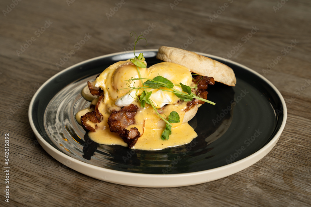 Eggs Benedict with bacon and ham on a wooden table Eggs Benedict with bacon and ham on a wooden table