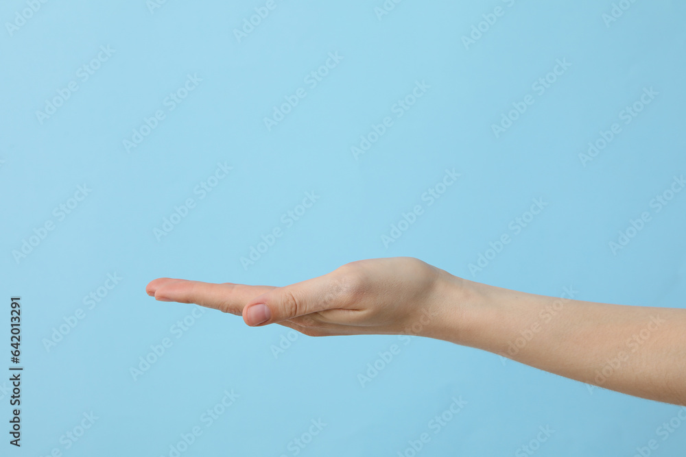 Female hand outstretched on light blue background Female hand outstretched on light blue background