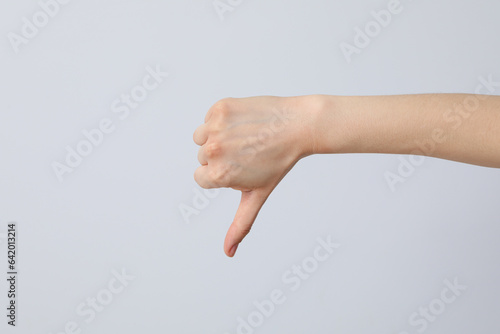 Female hand showing finger down on grey background