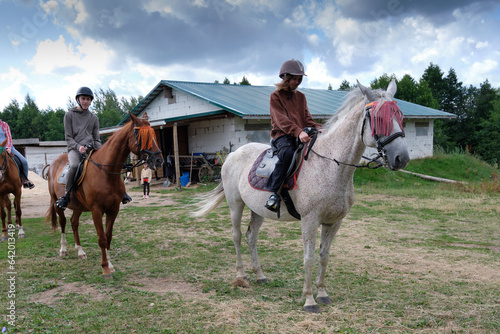 A young girl and a boy riding horses. The concept of interaction between children and horses