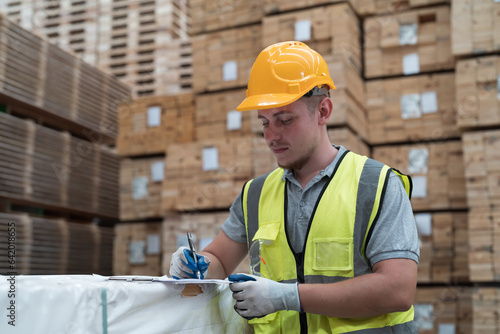 Male warehouse worker wearing uniform checks stock inventory in wooden warehouse storage. Male worker working in wooden warehouse photo