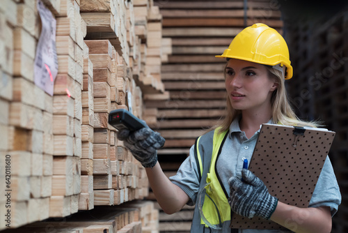 Female warehouse worker scanning barcodes on pile of plank wooden in wooden warehouse storage. Woman worker working in wood warehouse storage