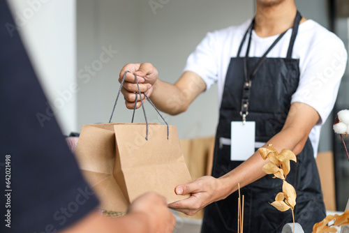 Closeup of man serving customer in a store with shopping bag.