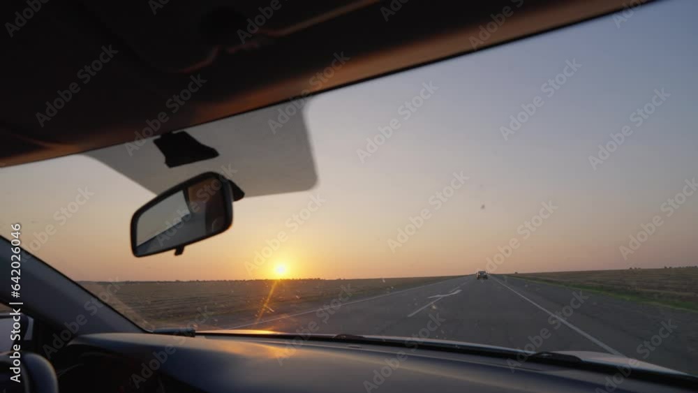 View from the Inside of a Driving Car on the Highway at Sunset. Windshield of a Vehicle While Driving on the Road. Travel and Trip Concept. View from the Inside of a Driving Car on the Highway at Sunset. Windshield of a Vehicle While Driving on the Road. Travel and Trip Concept.