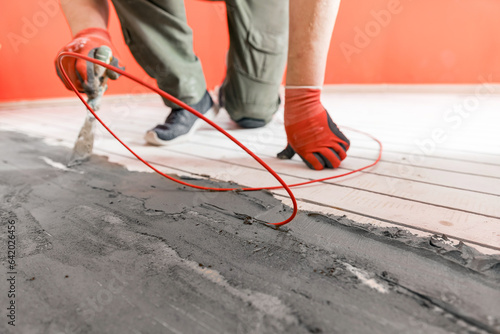 Master builder install red electric cable in concrete floor for heating