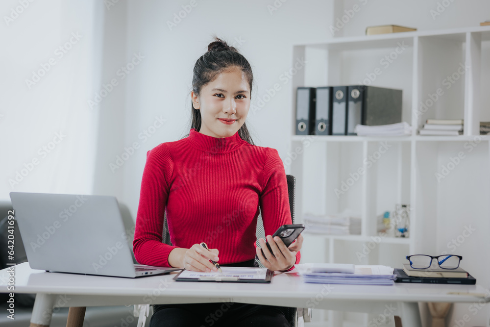 Successful Asian woman at work, beautiful smiling, happy working with laptop and smart phone in office at home. modern work Successful Asian woman at work, beautiful smiling, happy working with laptop and smart phone in office at home. modern work