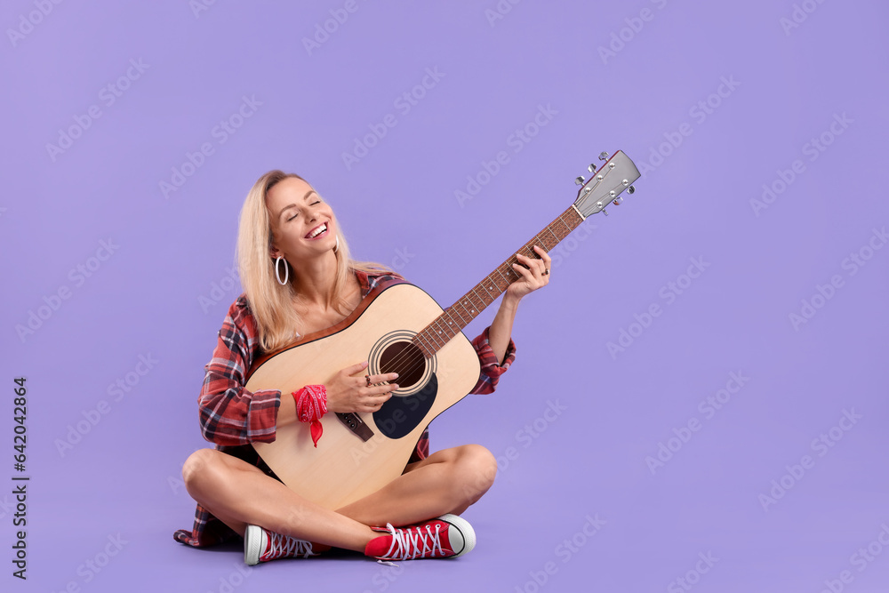 Happy hippie woman playing guitar on purple background. Space for text Happy hippie woman playing guitar on purple background. Space for text