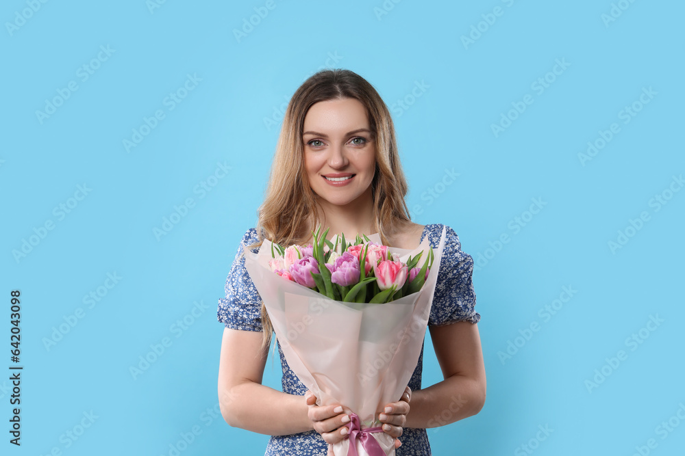 Happy young woman with bouquet of beautiful tulips on light blue background Happy young woman with bouquet of beautiful tulips on light blue background