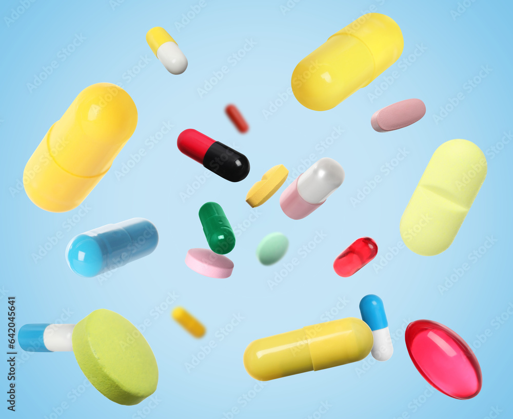 Many different colorful pills falling on light blue background Many different colorful pills falling on light blue background