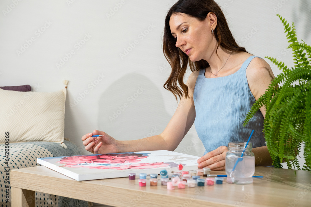 Painting by numbers. Woman drawing picture by numbers with acrylic paints on canvas at home. Painting on canvas for beginners. Creative hobby. Selective focus. Painting by numbers. Woman drawing picture by numbers with acrylic paints on canvas at home. Painting on canvas for beginners. Creative hobby. Selective focus.