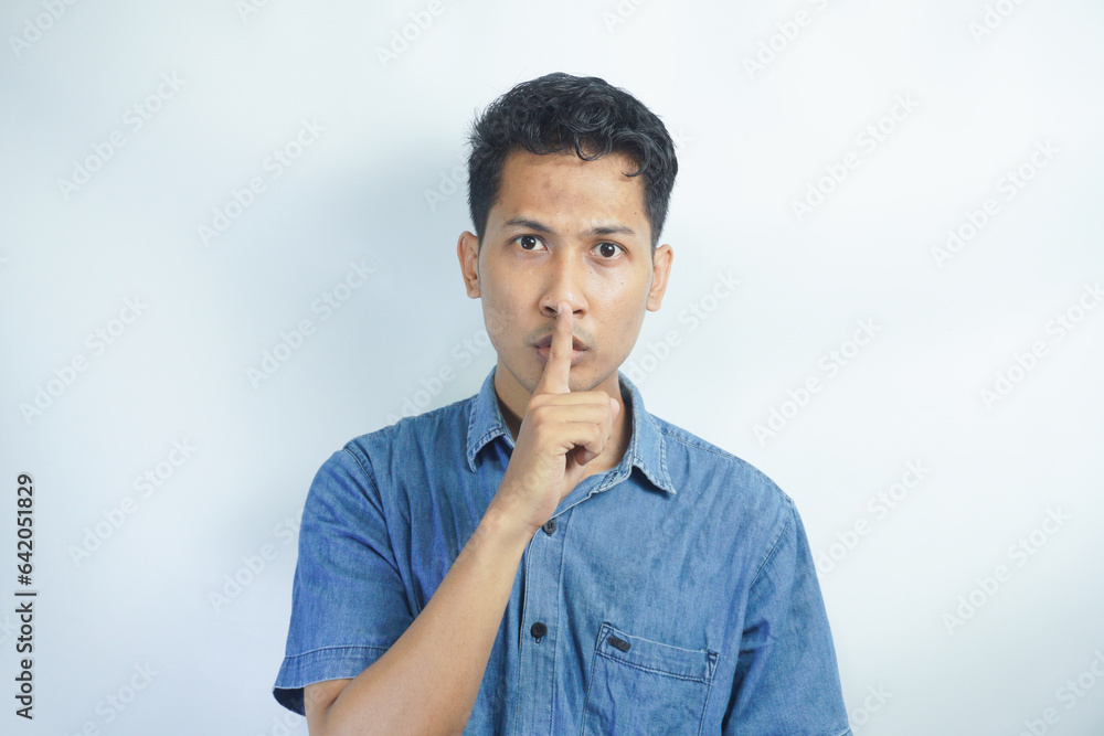 Serious good looking male with trendy hairdo, keeps fore finger on lips, tries to keep conspiracy, says: Shh, make silence please. Isolated shot of attractive man shows silence sign Serious good looking male with trendy hairdo, keeps fore finger on lips, tries to keep conspiracy, says: Shh, make silence please. Isolated shot of attractive man shows silence sign