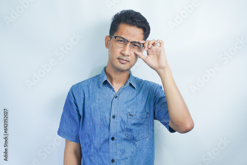 Indoor picture of young business man in glasses pictured isolated on white background looking straight at camera, showing confidence and providing stability for employees © AriaSandi