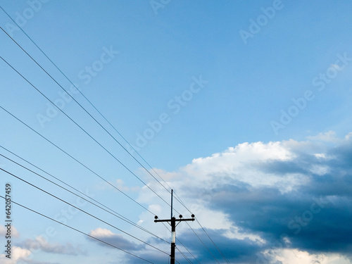 Rural electricity poles against a backdrop of blue sky and clouds.