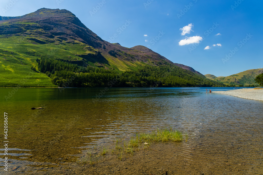 Shoreline of a tranquil, calm lake with beautiful mountain scenery in summer