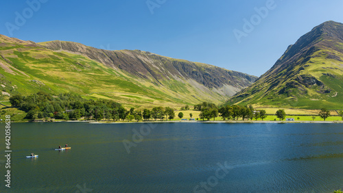 Fototapeta Naklejka Na Ścianę i Meble -  Kayaks and paddleboards on a calm, peaceful lake surrounded by tall mountains (Buttermere, Lake Distrtict)
