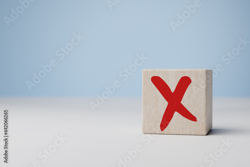 Red cross mark, x, wrong mark sign, red cross sign on edge of wooden cube. Concept of negative decision making or choice of rejection.