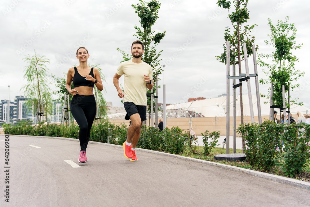 Motivation friends engaged in fitness running who train together. People using smart watches for fitness, sportswear and running shoes.    Athletes pair full-length training.