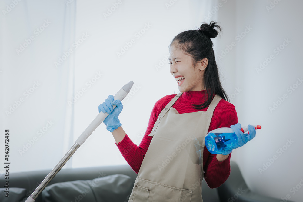 Happy Asian woman cleaning the house Hold the mop like you use a microphone. Housewives enjoy creative chores and house cleaning. Happy Asian woman cleaning the house Hold the mop like you use a microphone. Housewives enjoy creative chores and house cleaning.