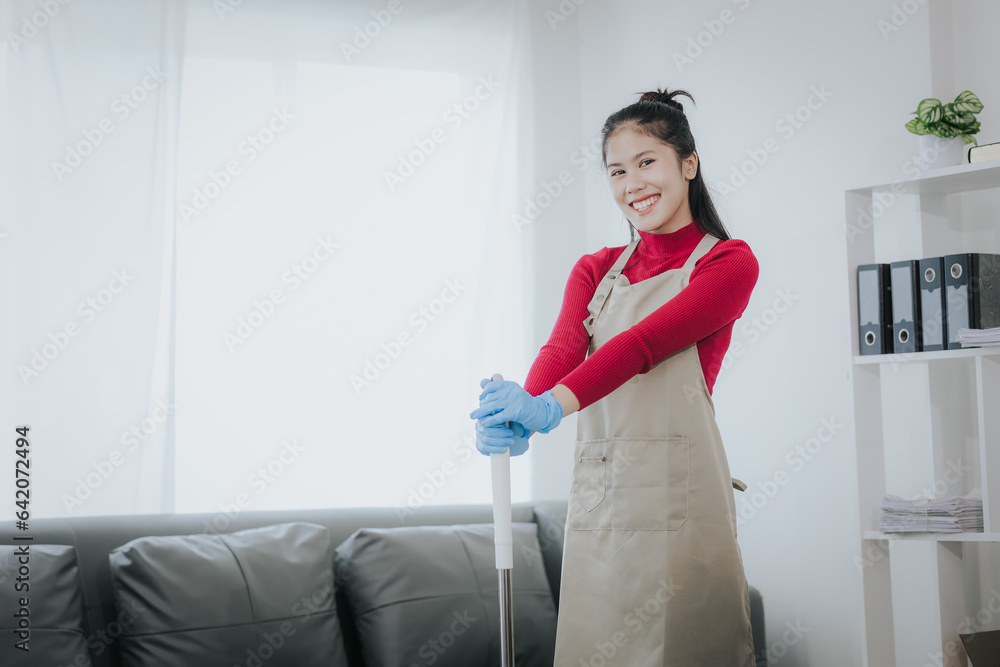 Happy Asian woman cleaning the house Hold the mop like you use a microphone. Housewives enjoy creative chores and house cleaning. Happy Asian woman cleaning the house Hold the mop like you use a microphone. Housewives enjoy creative chores and house cleaning.