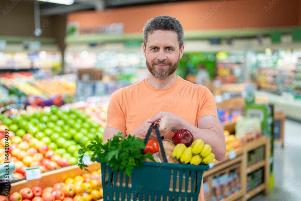 Man with grocery basket shopping at supermarket. Grocery store, shopping basket. Banner with man for grocery food store or supermarket. Man choosing food in store or grocery store.