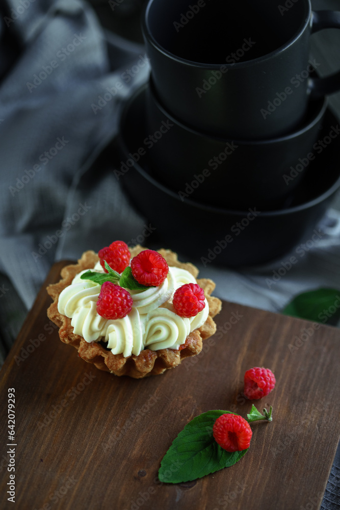 Cake with cream and raspberries with mint leaves on wooden vintage background Cake with cream and raspberries with mint leaves on wooden vintage background