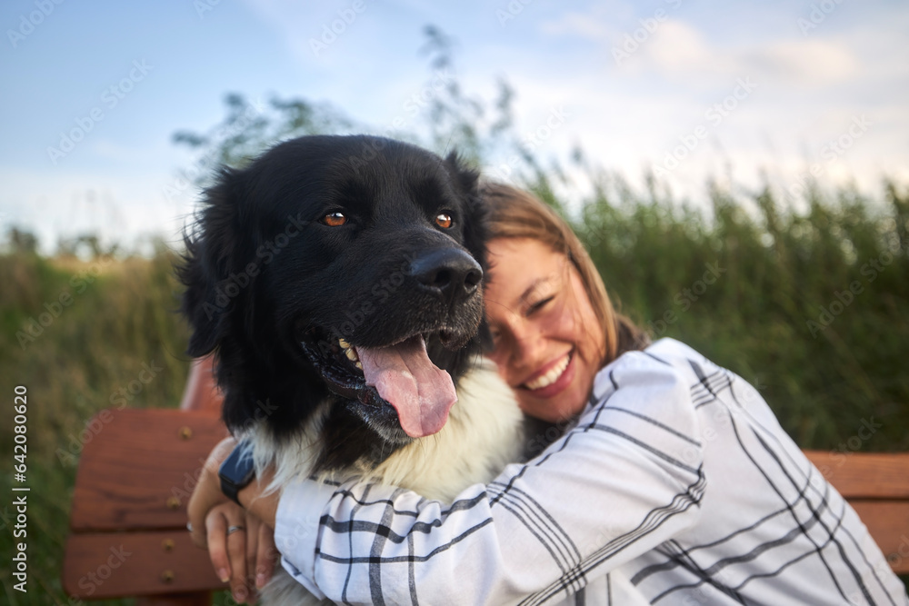 Φωτογραφία Happy teen girl hugging her dog on wooden bench