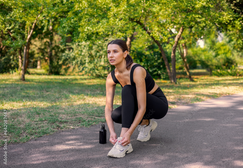 girl running in park, tie the laces and drinking water from bottle. beautiful woman in park fit body shape, practising sport. summer time, healthy lifestyle girl running in park, tie the laces and drinking water from bottle. beautiful woman in park fit body shape, practising sport. summer time, healthy lifestyle