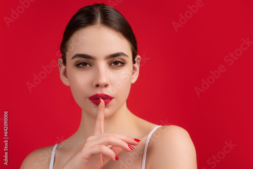 Say secret hush be quiet with finger on lips. Shhh gesture isolated on studio background portrait. Girl showing hush. Woman say secret hush be quiet with finger on lips, shhh gesture.