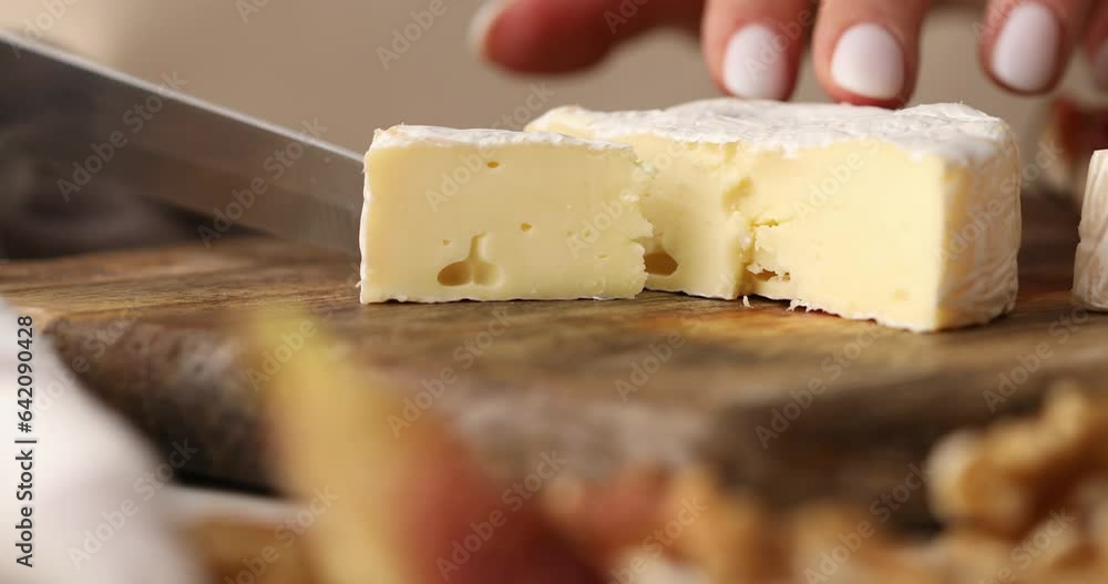 Female hands cutting brie cheese. Cheese with white mold. Preparing antipasto. Food close-up. Female hands cutting brie cheese. Cheese with white mold. Preparing antipasto. Food close-up.