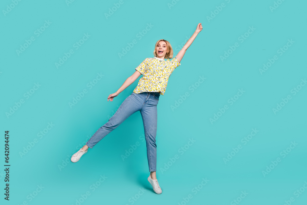 Full length photo of excited cheerful girl dressed yellow print t-shirt catching arm empty space isolated teal color background