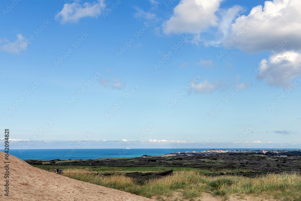 Panorama of sand dunes and blue sea. Seascape with people resting and walking near the sea on a summer day.