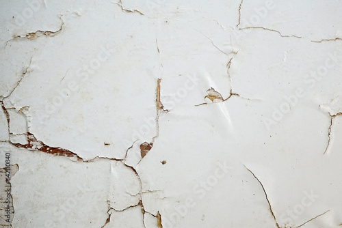 Grunge style urban weathered shabby white peeled painted concrete surface of the wall with holes, dirty and cracks