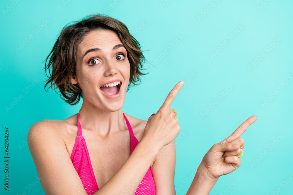 Photo of astonished cheerful girl open mouth dressed pink tank two arms direct empty space sale off isolated on cyan color background Photo of astonished cheerful girl open mouth dressed pink tank two arms direct empty space sale off isolated on cyan color background