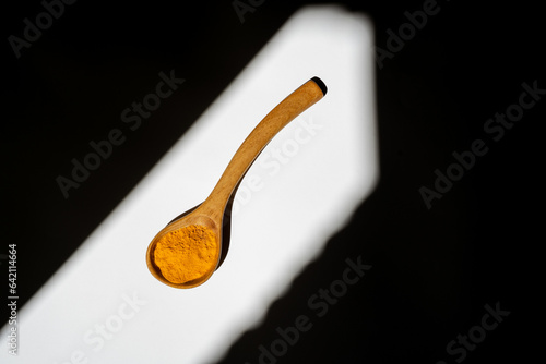 A wooden spoon with yellow turmeric.