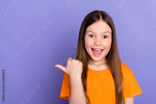 Portrait of cute young girl preschool age wear orange t shirt having fun direct finger mockup event isolated on purple color background