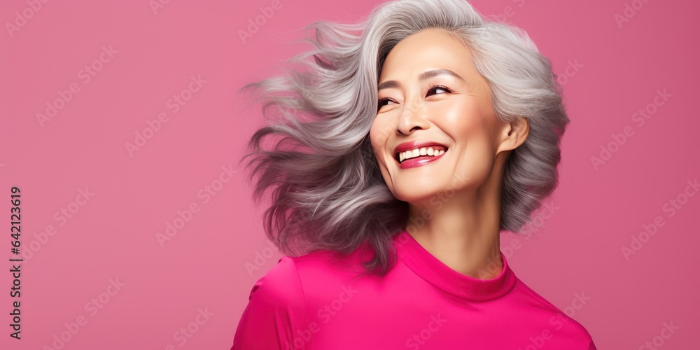 A stylish Asian woman in her 50s. Luxurious middle-aged woman with a short hairdo on pink background. She is smiling and looking at copy space. A stylish Asian woman in her 50s. Luxurious middle-aged woman with a short hairdo on pink background. She is smiling and looking at copy space.